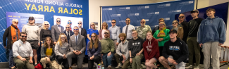 Members of UNE's Community pose in front of a mural inside the Alfond Forum